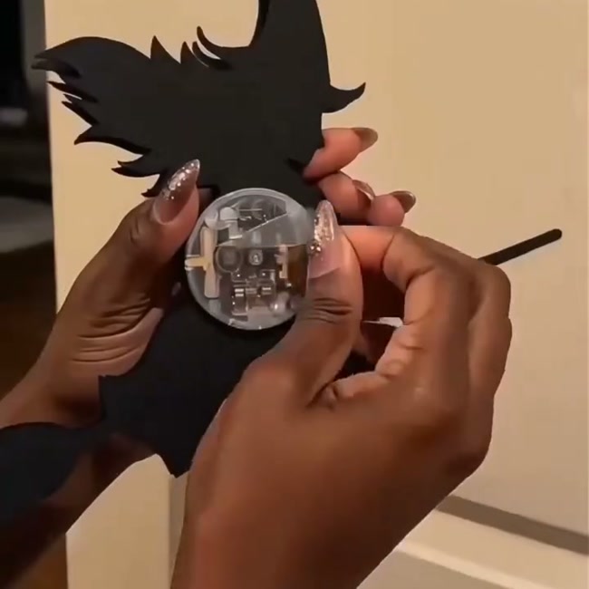 Hands holding a witch silhouette, showing the round LED light module on the back